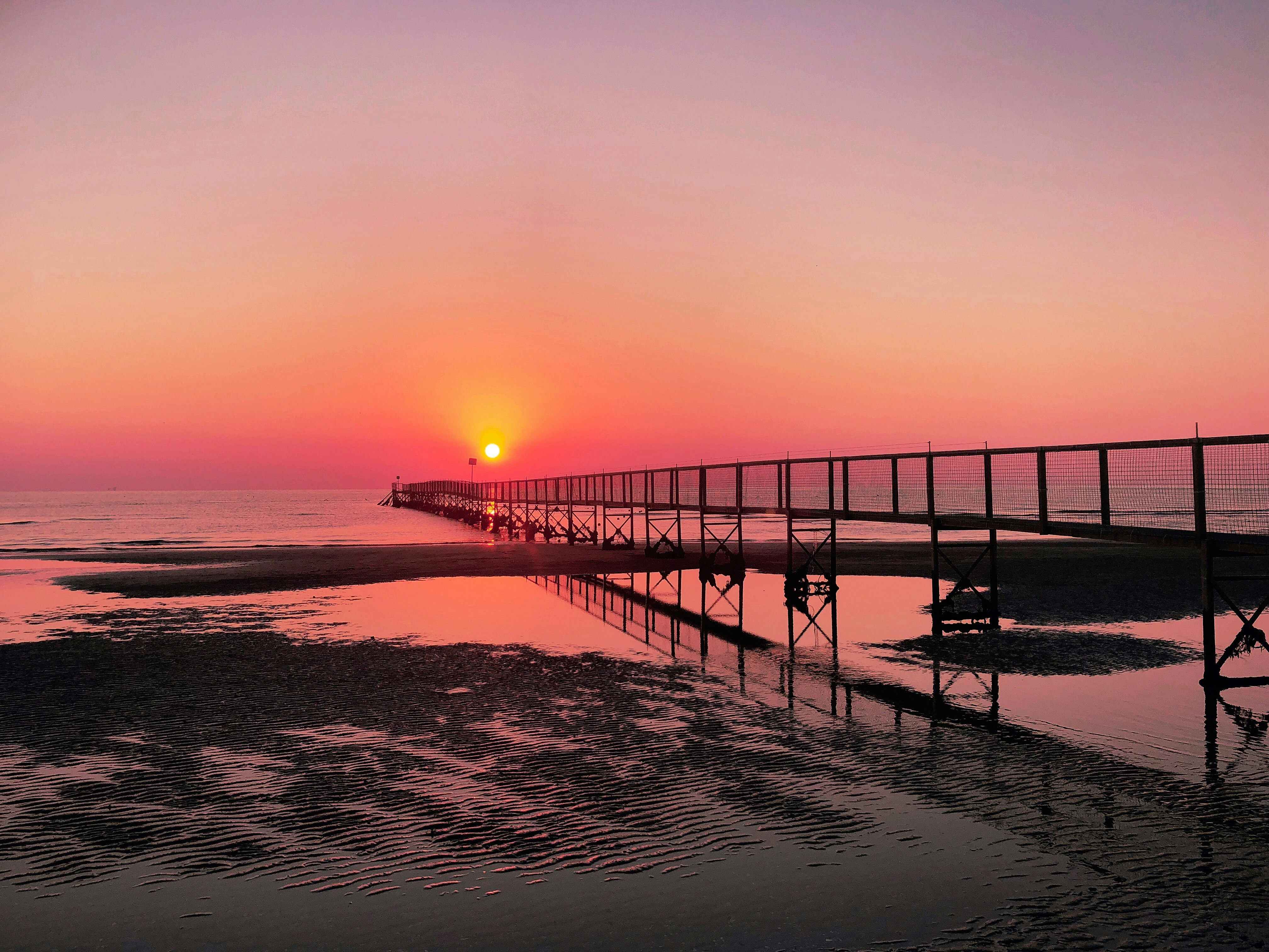 silhouette of dock on sea during sunset